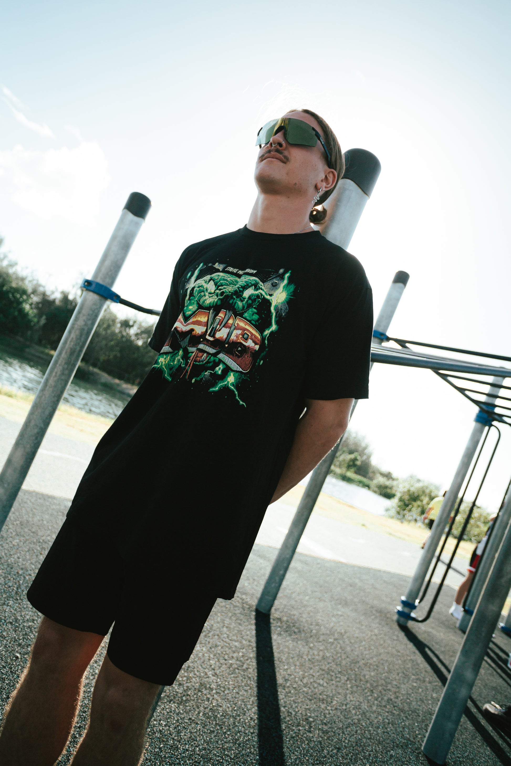 Person wearing a black t-shirt with a graphic design, standing on a playground.