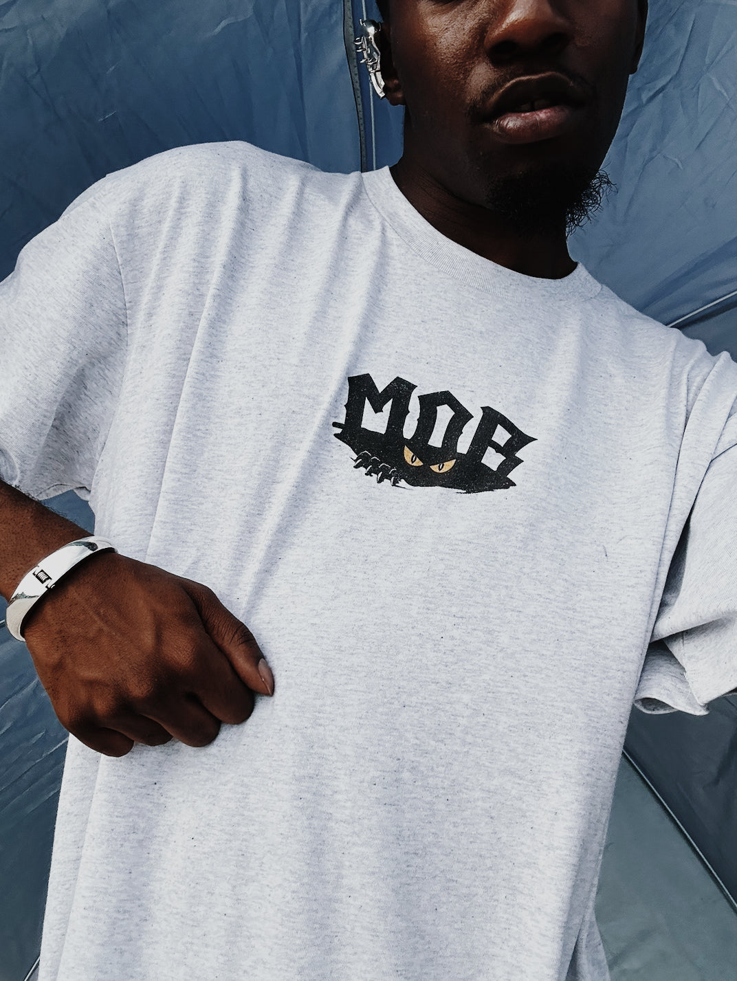 Person wearing a white t-shirt with a logo, standing against a blue background