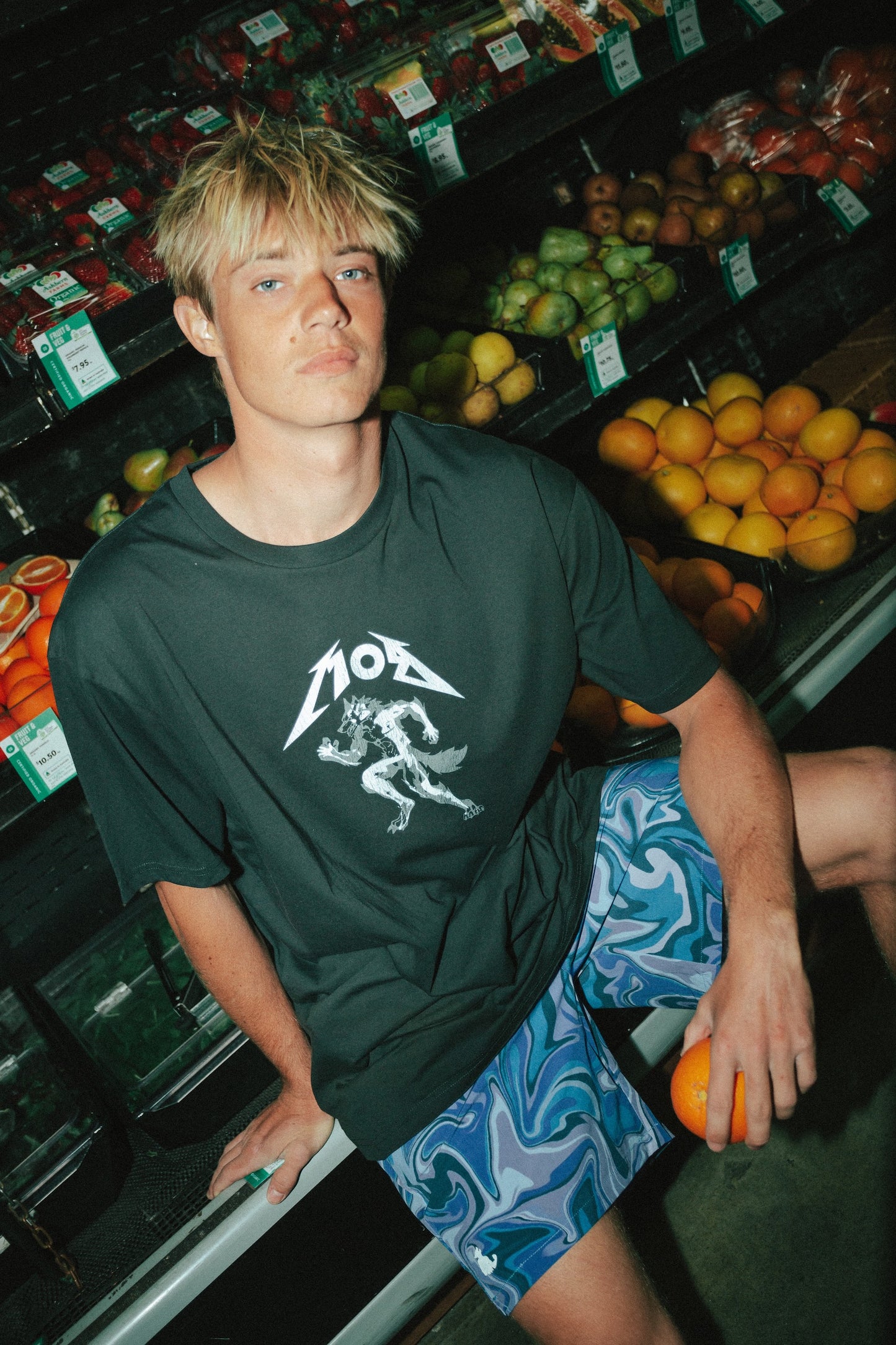 Person wearing a dark t-shirt with a logo in a grocery store aisle.