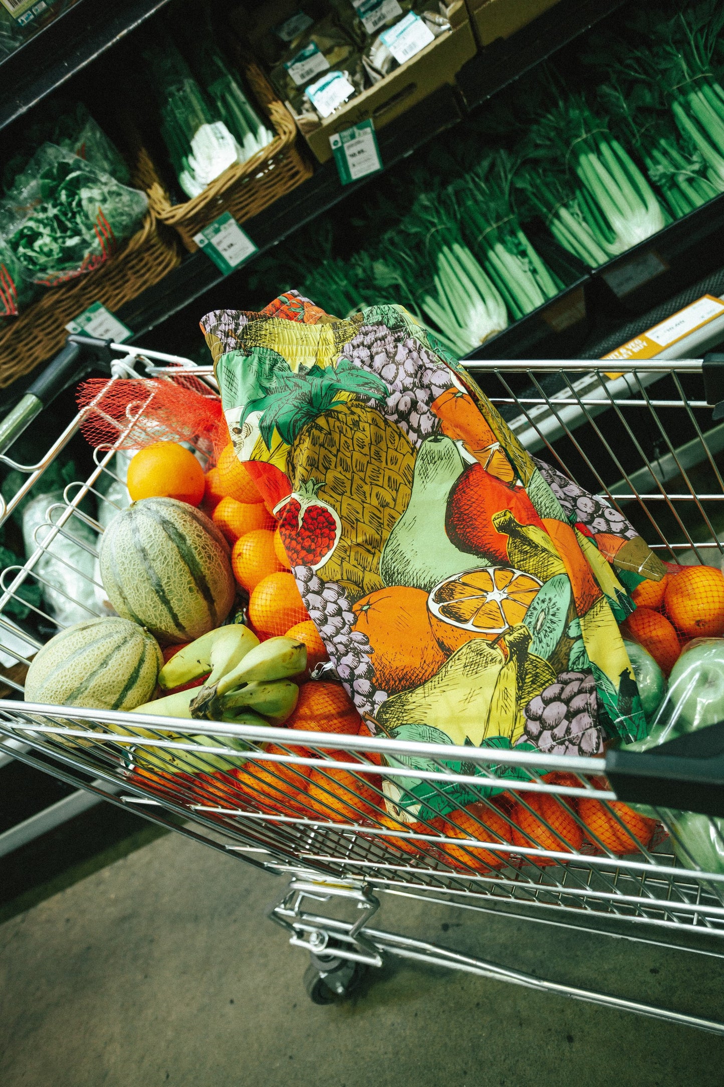 Framed artwork of fruits and vegetables displayed in a grocery cart.