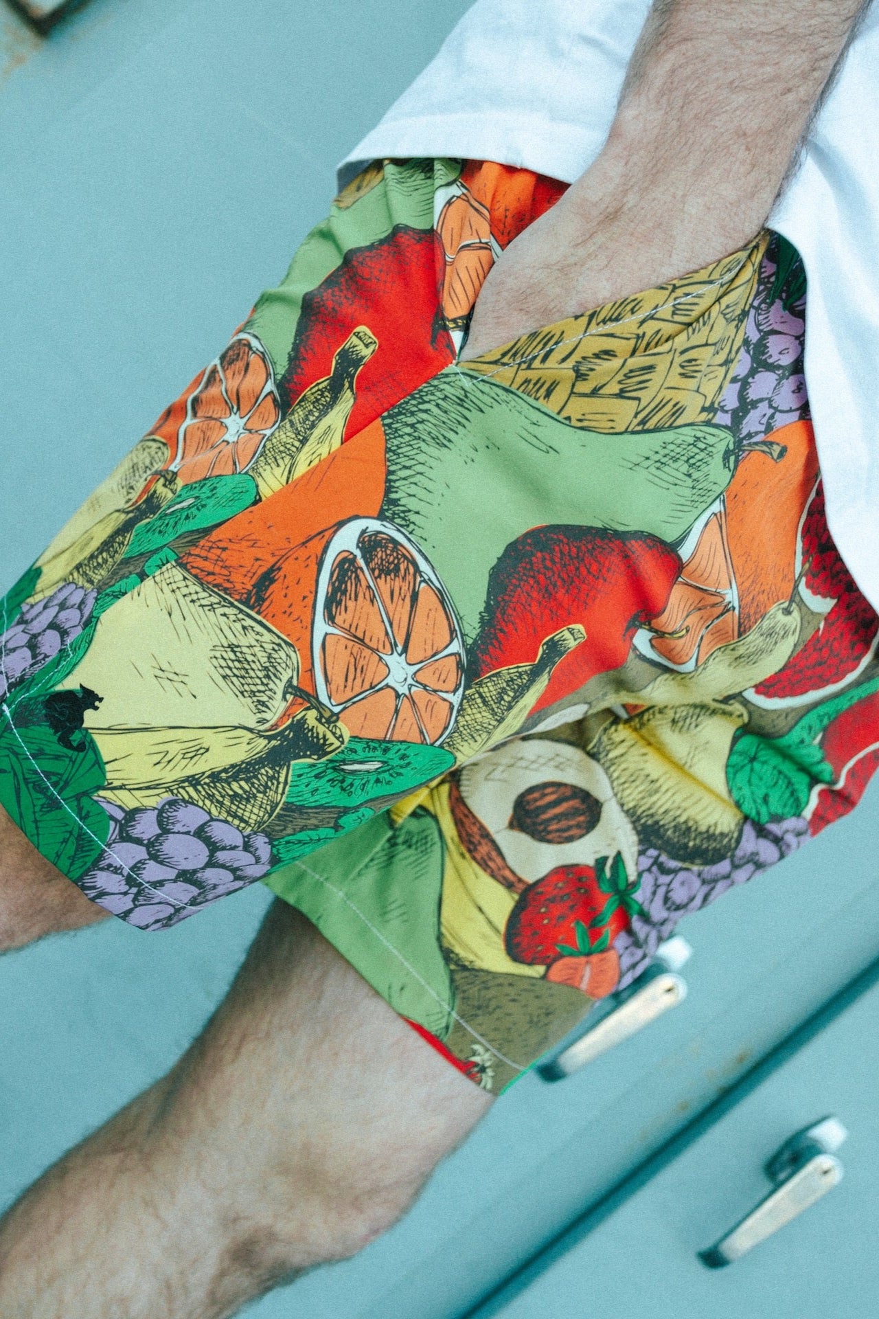 Colorful fruit-patterned shorts worn by a person on a light blue background